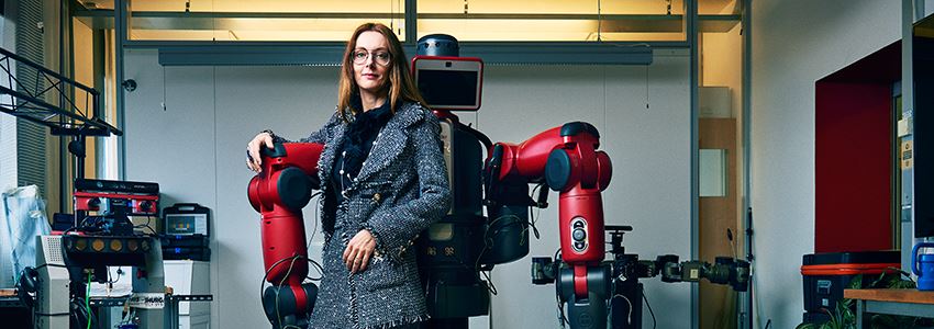 Danica Kragic Jensfelt, professor och robotforskare vid KTH, lutar sig mot en robot